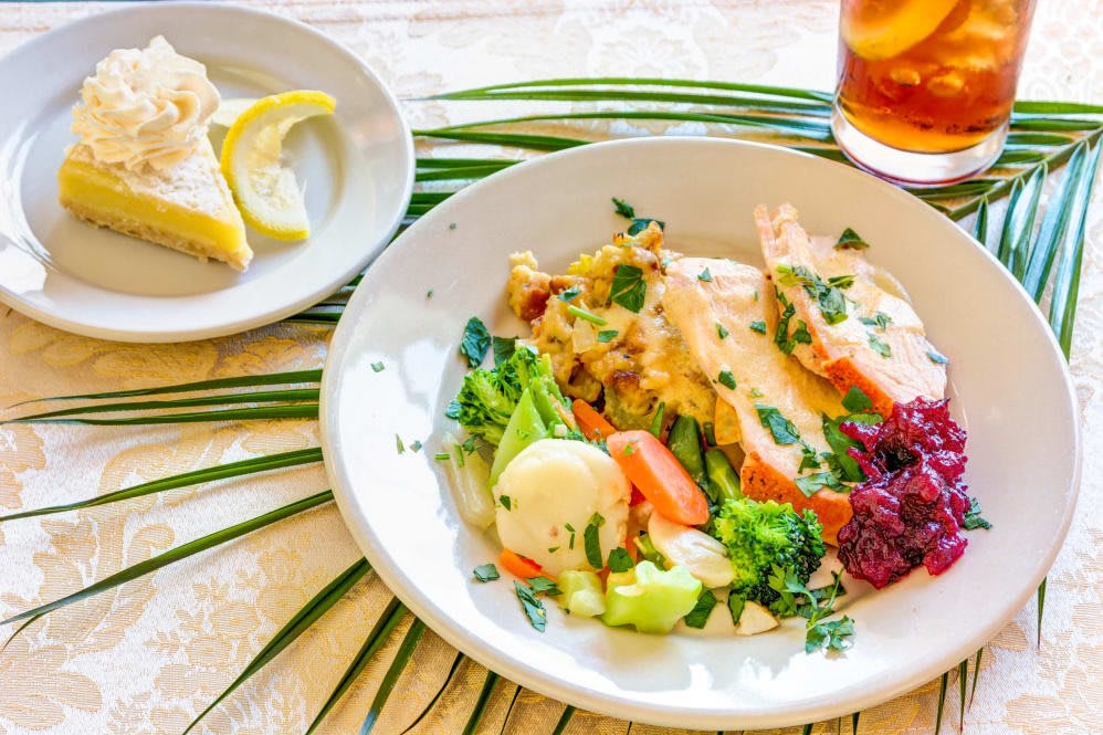 A plate of chicken with mixed vegetables and a side salad, served with lemon wedges.