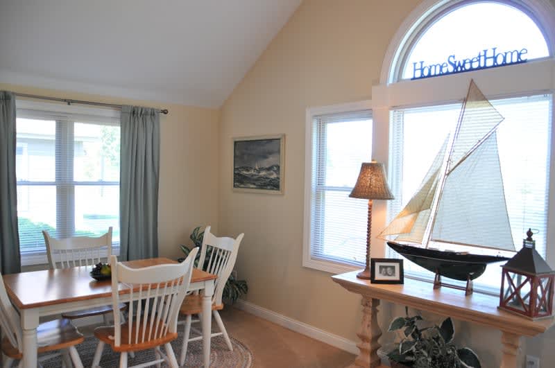 A cozy dining area with a nautical-themed decor featuring a table with chairs, soft lighting, and a boat model by the window.