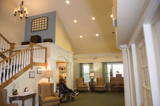 A spacious living room with high ceilings, comfortable seating, and large windows.