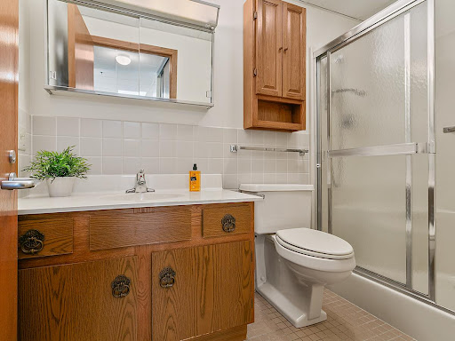 A well-lit bathroom featuring a wooden vanity, a shower, and essential fixtures.