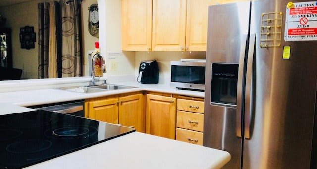 A modern kitchen with wooden cabinets, featuring a refrigerator, microwave, and coffee maker.