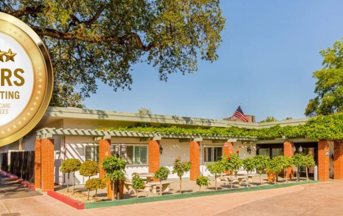 A single-story building surrounded by greenery on a sunny day.