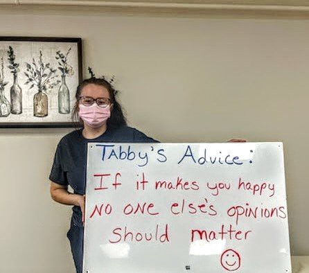 A person stands next to a whiteboard displaying motivational advice.