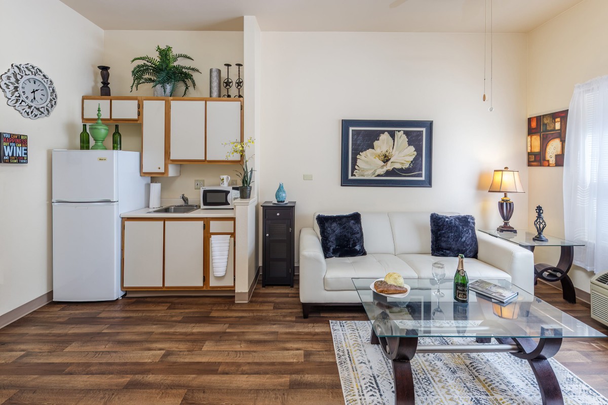 A cozy living area with a white couch, kitchenette, and modern decor.