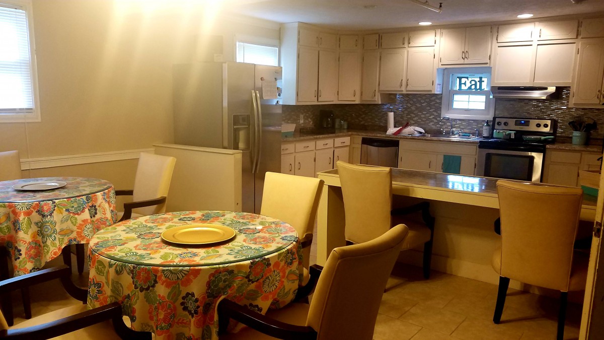 A cozy kitchen and dining area with a round table covered in a colorful tablecloth.