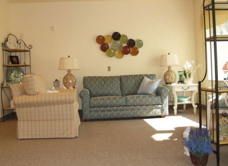 A cozy living room with a blue sofa, accented by two lamps and colorful wall art.