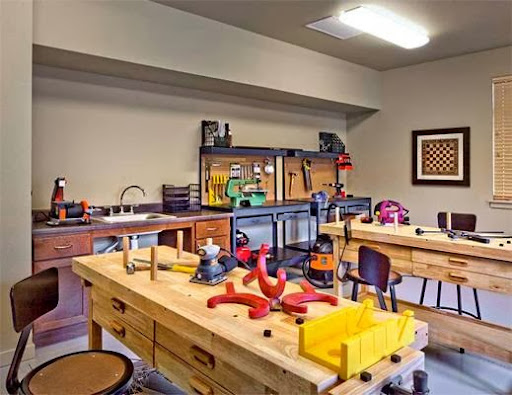 A well-equipped workshop featuring multiple workbenches and various tools for woodworking and crafting.