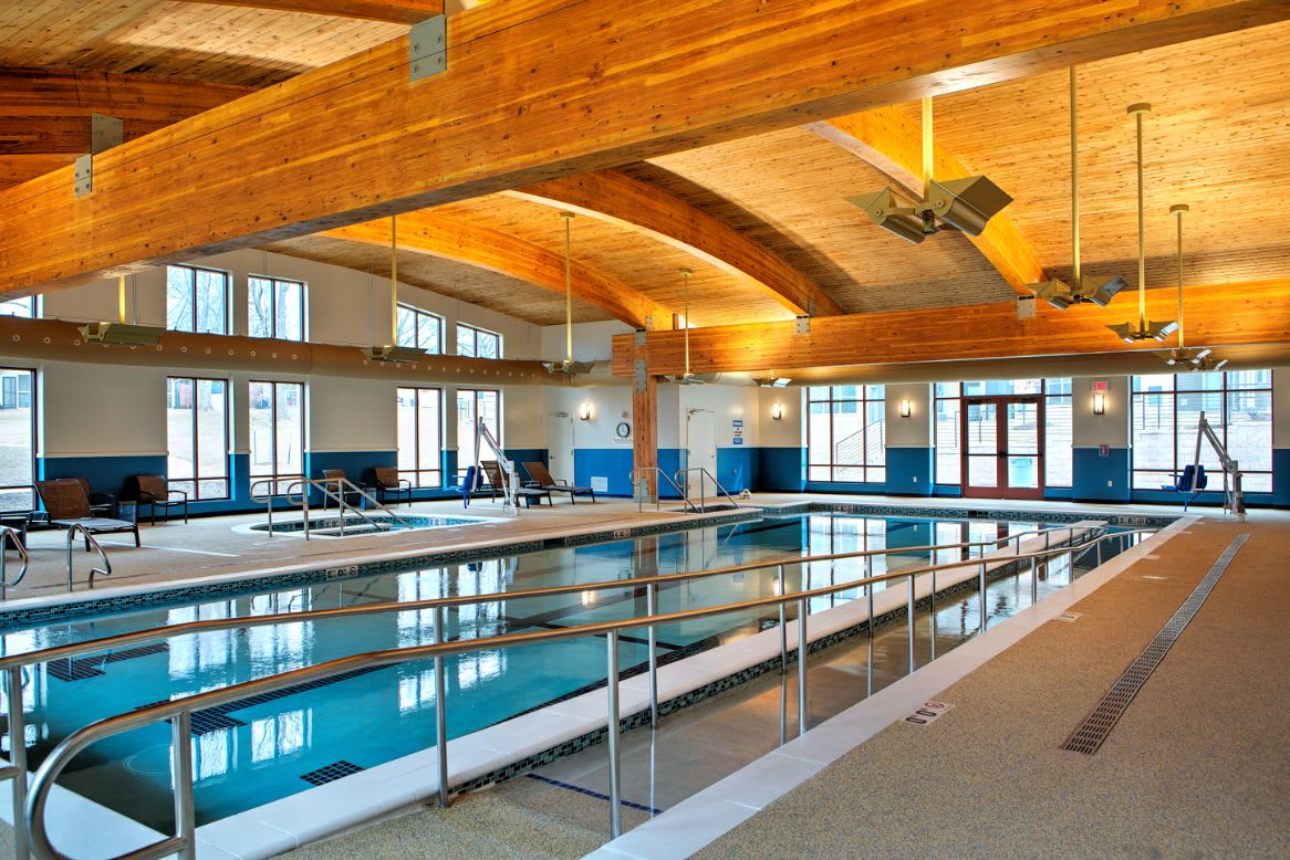 An indoor swimming pool featuring a wooden ceiling and natural lighting.