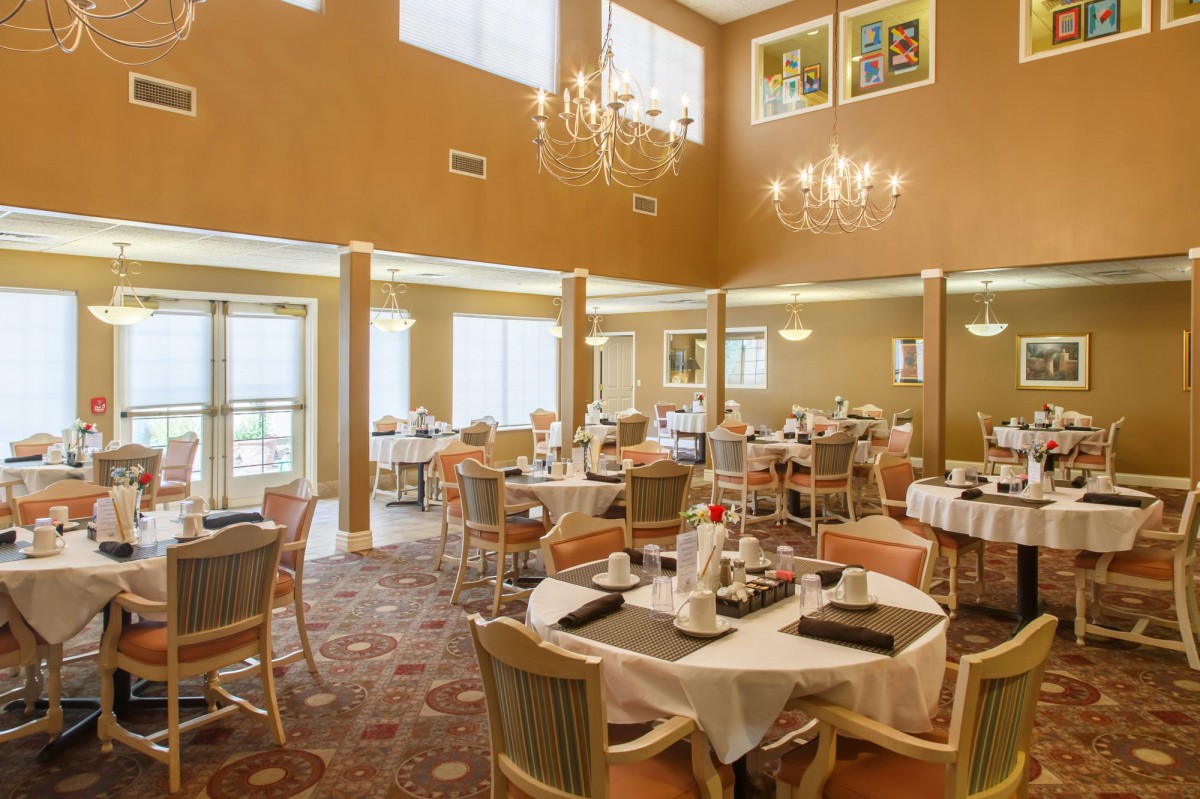 An elegant dining room setup with neatly arranged tables and chandeliers.