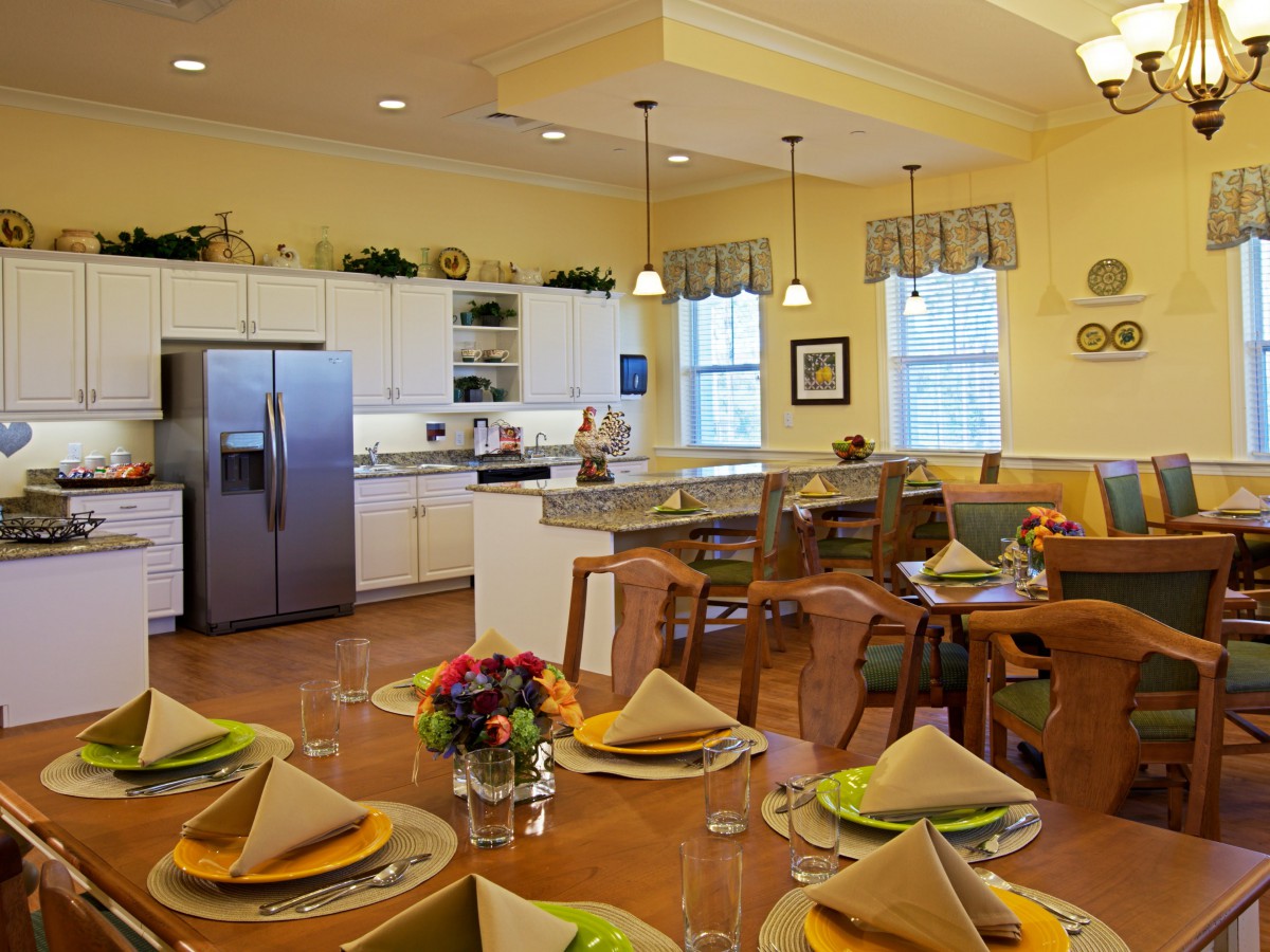 A modern kitchen and dining area with a neatly set table, featuring contemporary lighting and decor.