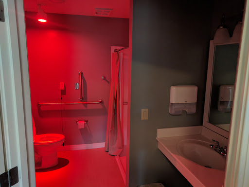 A visually striking bathroom illuminated with red light, featuring essential amenities like a toilet, sink, and shower.