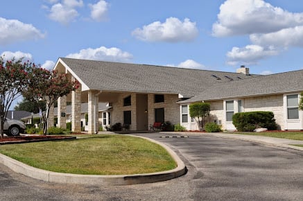 A residential building with an entrance and driveway under a cloudy sky.