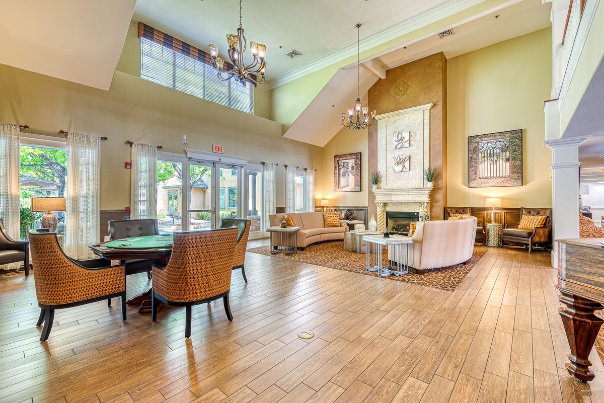 Spacious living room with high ceilings, elegant chandeliers, and cozy seating.