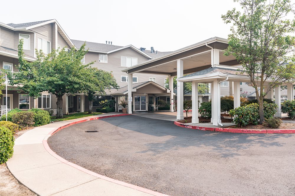 The entrance of a residential or commercial building with a driveway and surrounding greenery.