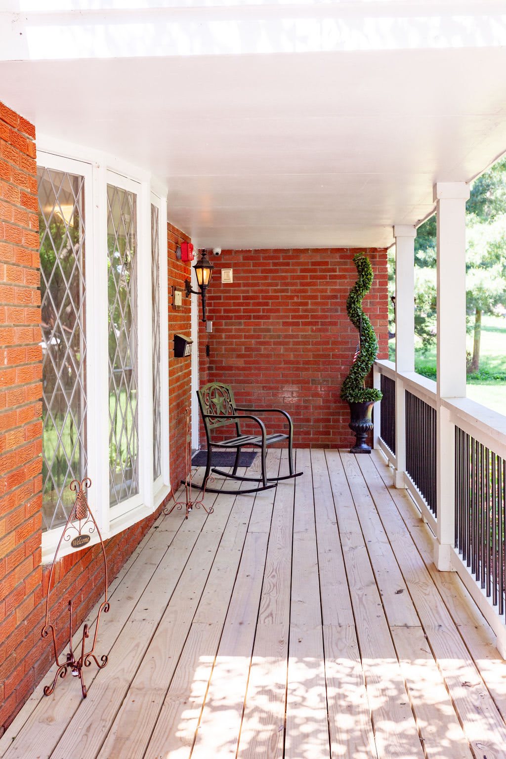 A cozy porch with a rocking chair, potted plant, and wooden floor.