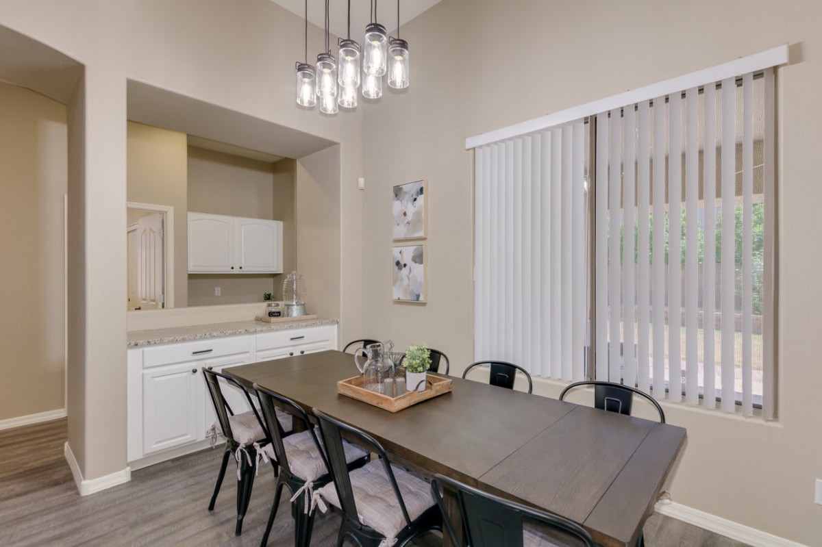 A modern dining room with a minimalist design, featuring a large table and several chairs under contemporary lighting.