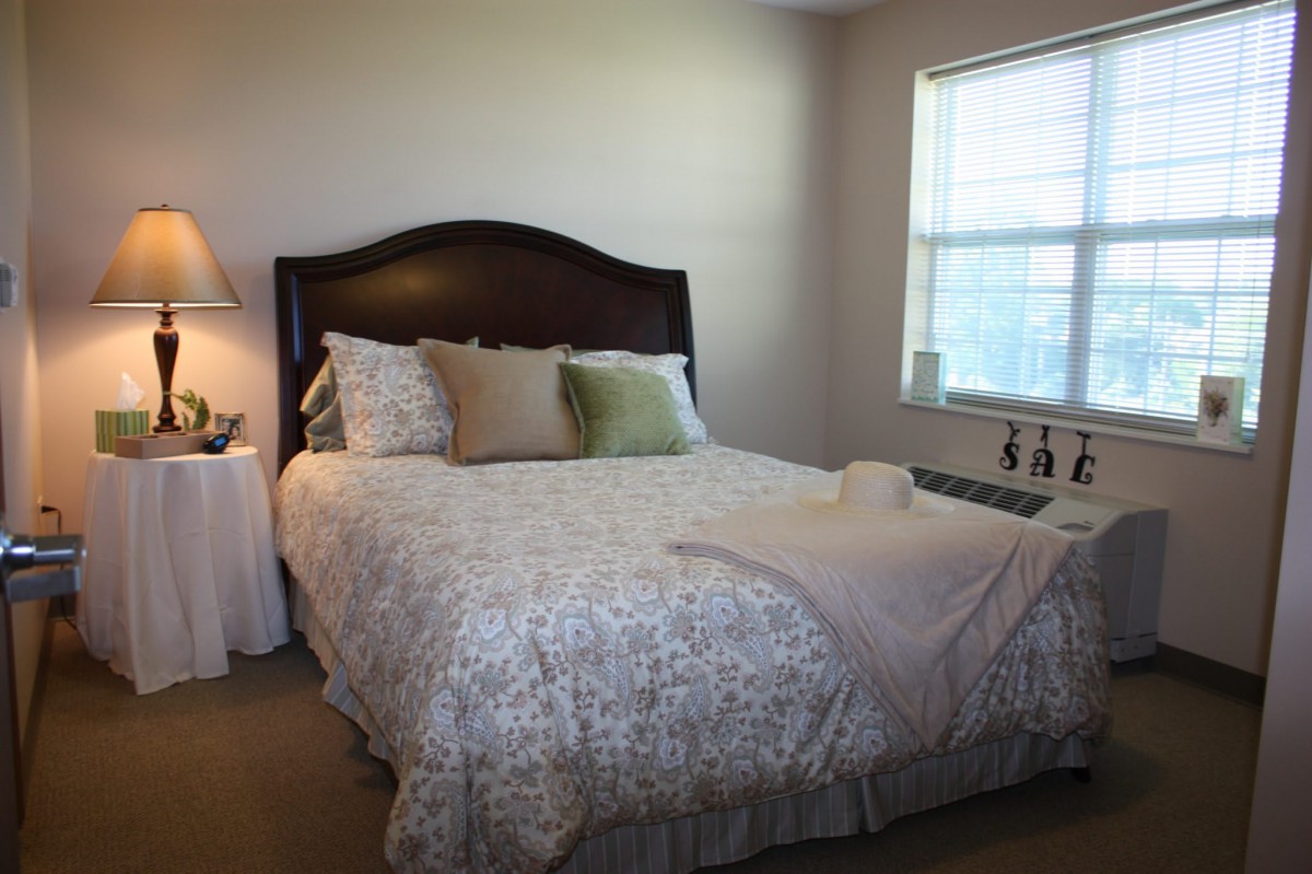 A cozy bedroom with a neatly made bed, soft pillows, and natural light from the window.