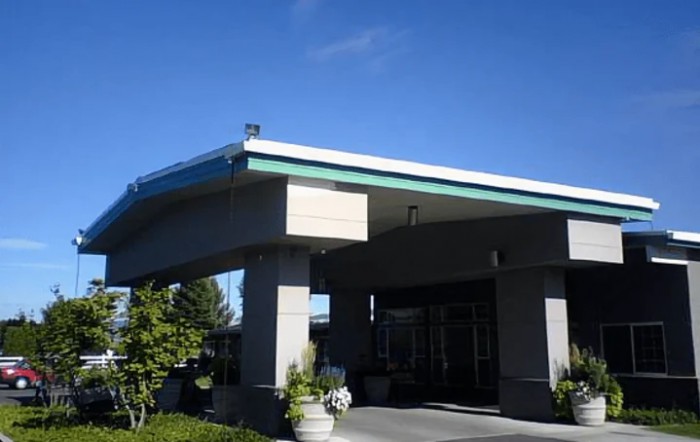 A building entrance with a covered walkway under a clear blue sky.