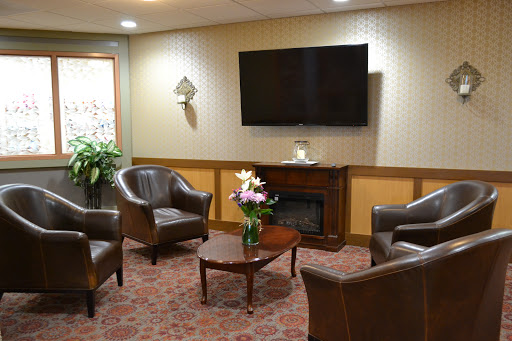 A cozy lounge area featuring comfortable seating, a television, and decorative flowers.