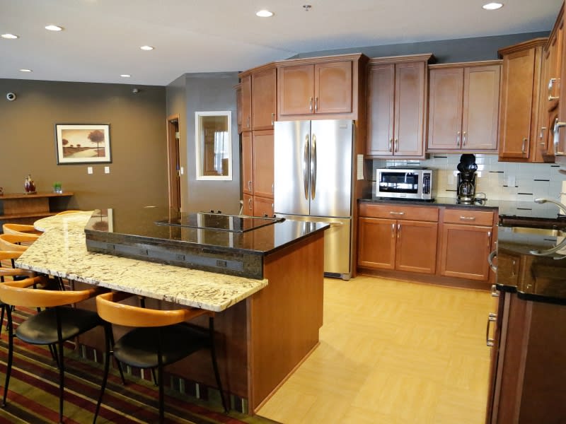 A modern kitchen featuring granite countertops, wood cabinets, and stainless steel appliances.