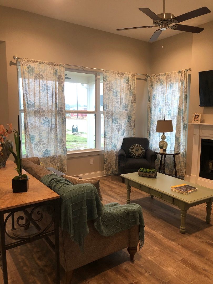 A cozy living room with a sofa, coffee table, and large windows letting in natural light.