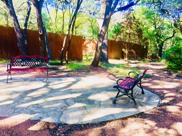 A peaceful garden setting with benches under the shade of trees.