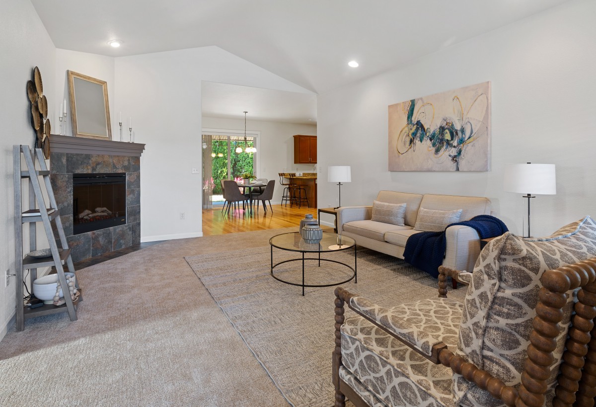 A modern living room featuring a comfortable sofa, stylish coffee table, and fireplace, complemented by artwork on the wall.