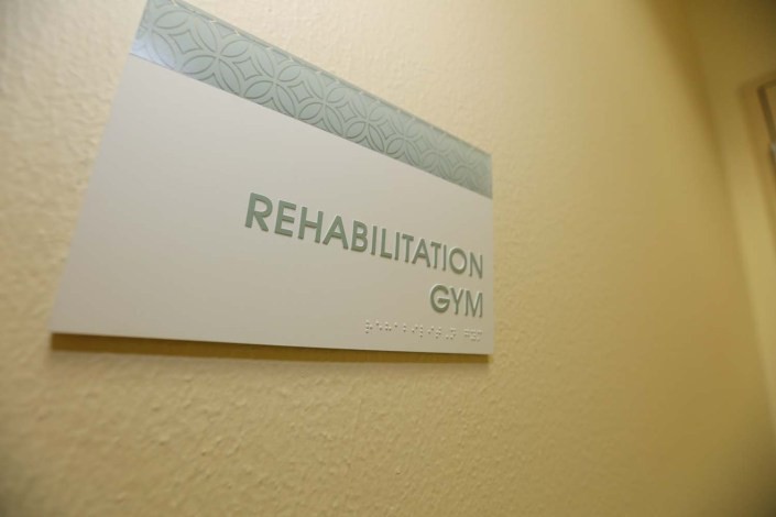 A sign on the wall indicating the location of a rehabilitation gym.
