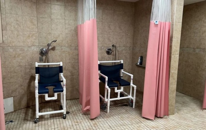 Accessible shower area with privacy curtains and equipped shower chairs.