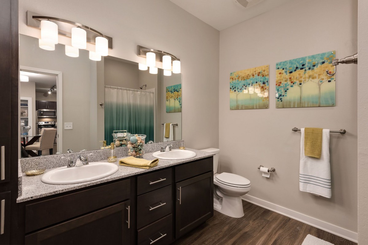A modern bathroom featuring a double sink vanity, decorative wall art, and elegant lighting.