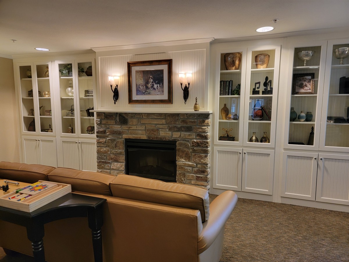 A cozy living room with a central fireplace, flanked by built-in bookshelves and illuminated by wall sconces.
