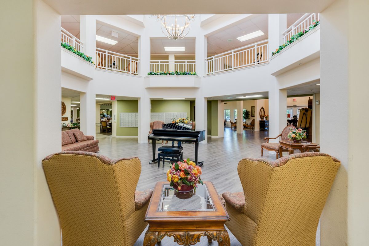 A spacious and elegantly designed lobby featuring a grand piano, comfortable seating, and a chandelier.