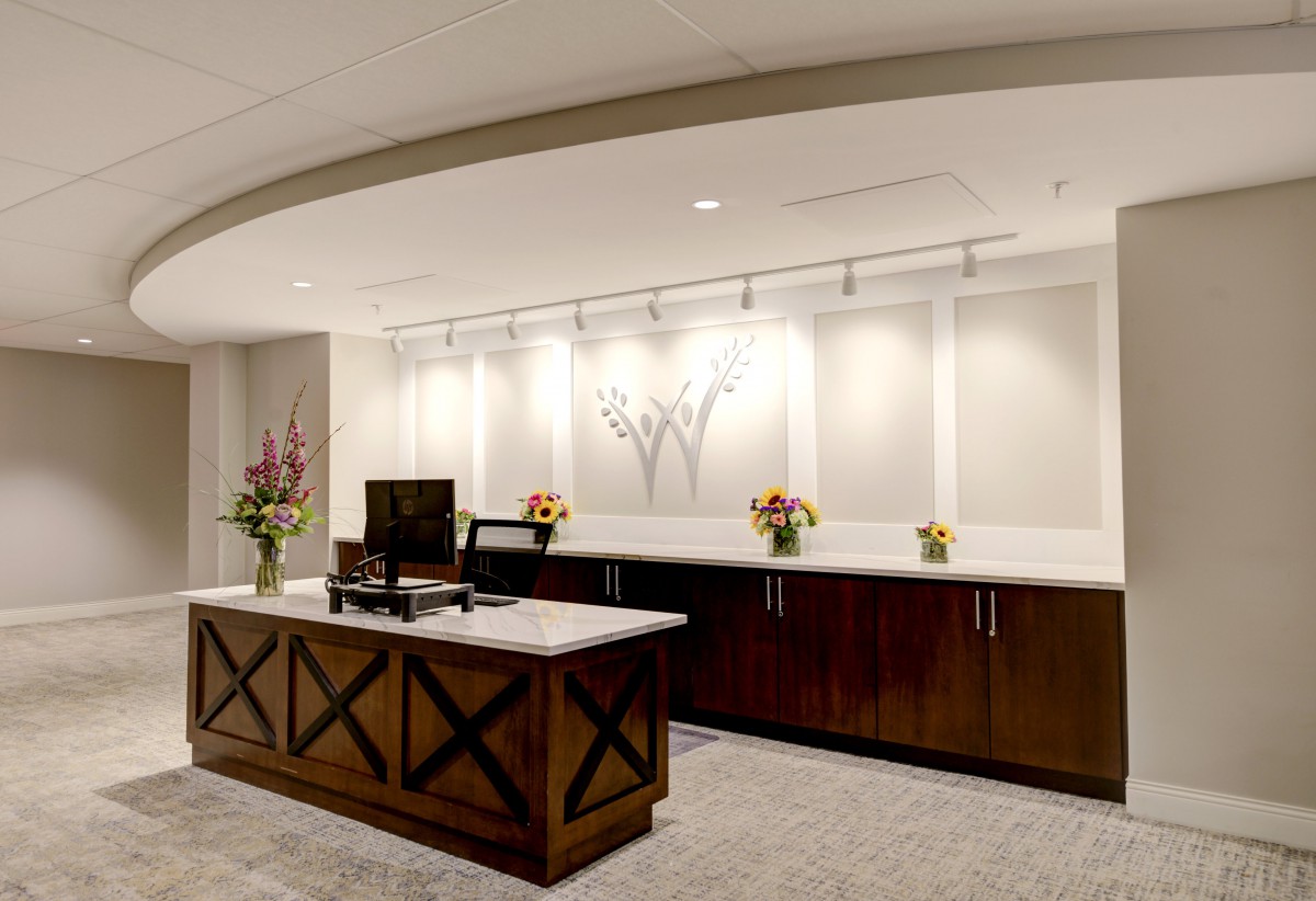 A modern reception area featuring a sleek desk with decorative flowers and ambient lighting.