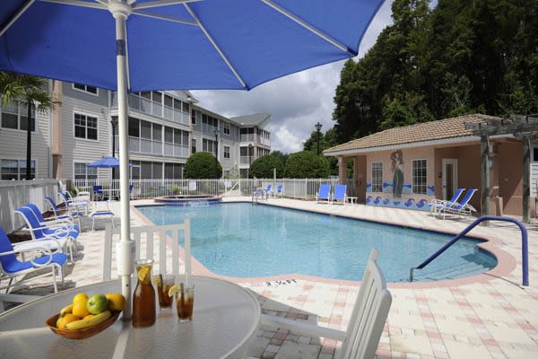 A tranquil outdoor resort swimming pool area with a patio table and umbrella.