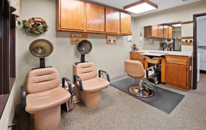 A cozy hair salon interior featuring salon chairs, hair dryers, and wooden cabinets.