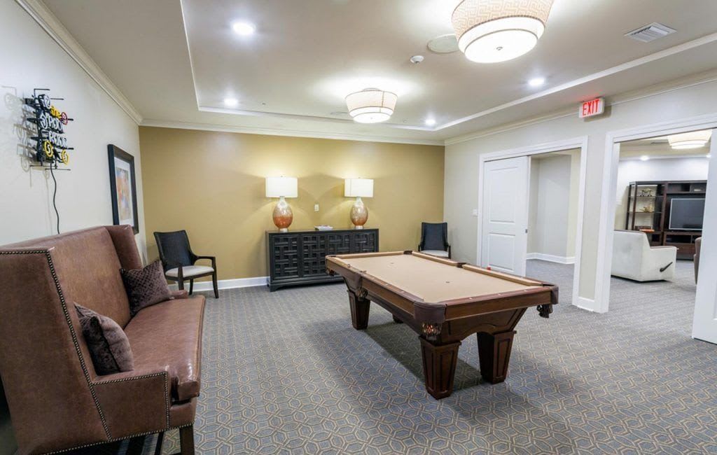 A stylish billiard room featuring a pool table, seating, and elegant lighting.