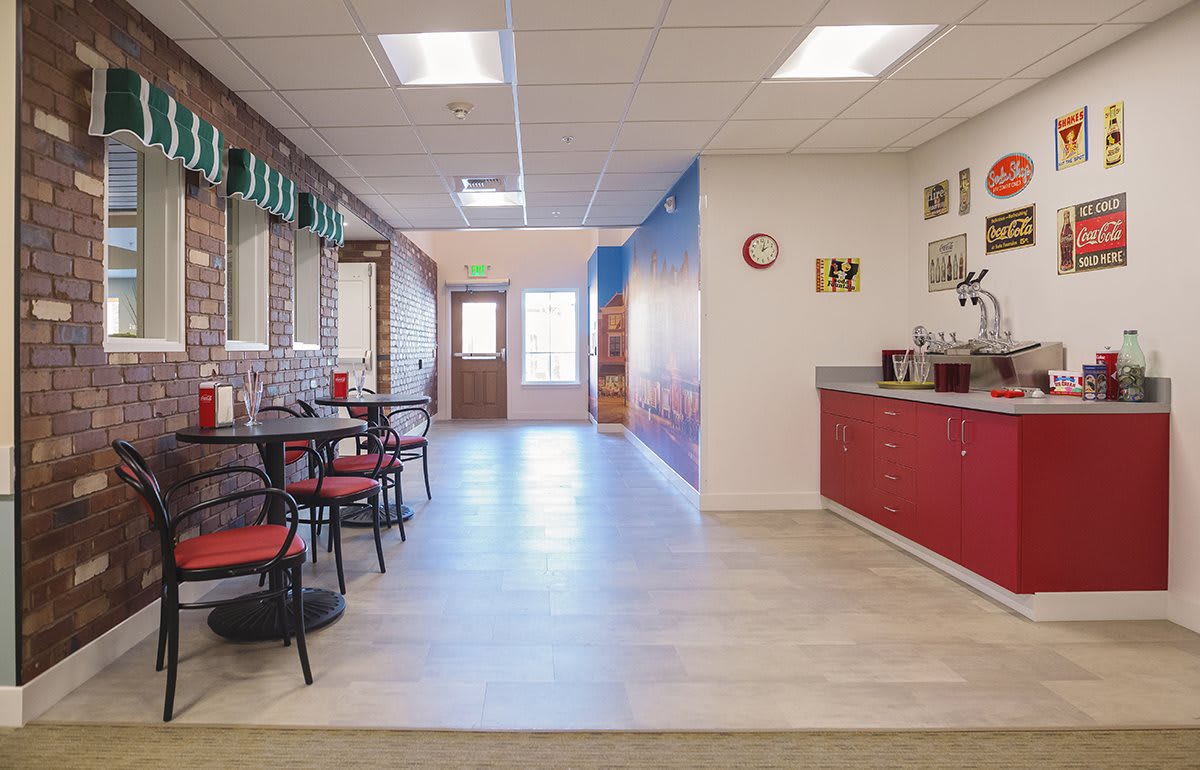 A modern cafeteria with red accents featuring tables and chairs, ample lighting, and a stylish decor.