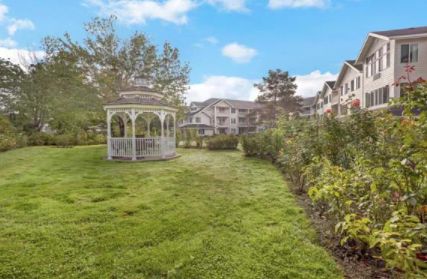 A serene garden with a gazebo and residential buildings in the background.