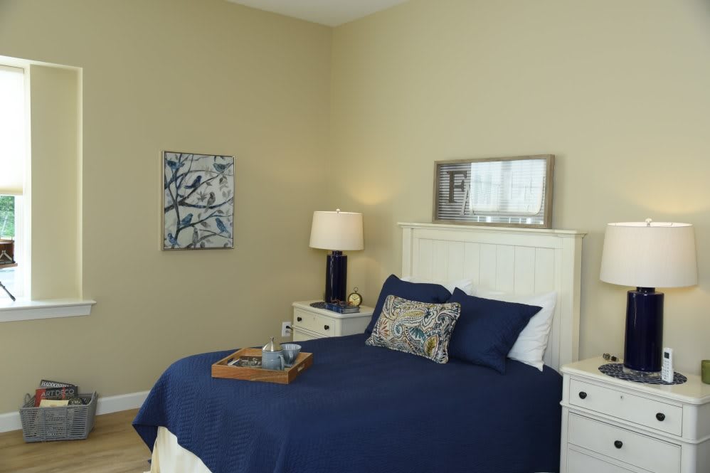 A modern bedroom with blue bedding, beige walls, and elegant decor.