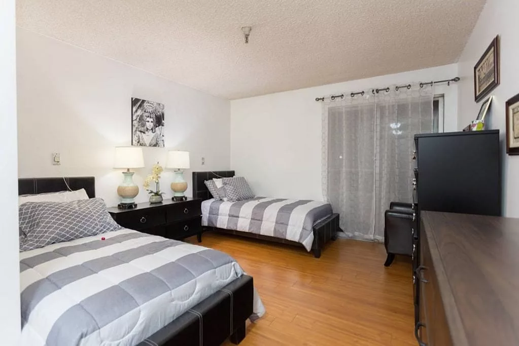 A cozy bedroom with two double beds, decorated with modern furniture and soft lighting.