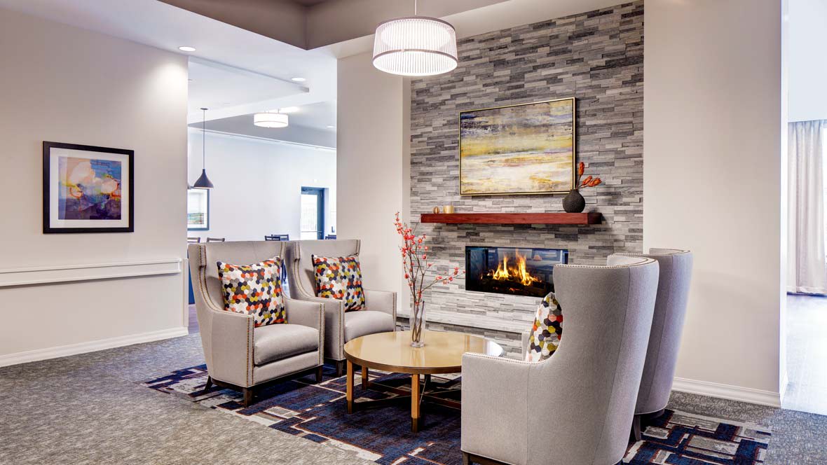 A modern living room with a cozy fireplace, stylish armchairs, and a wooden table in an elegant setting.