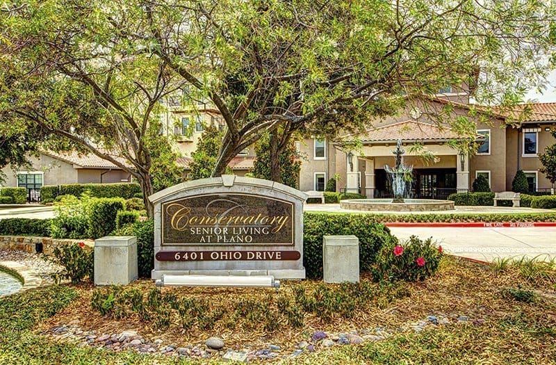 Entrance sign for a building surrounded by trees and landscaping.
