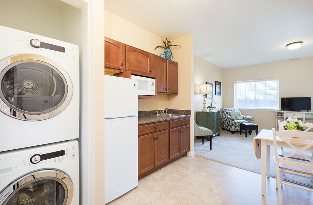 A cozy apartment interior featuring a compact kitchen with appliances and an adjoining living area.