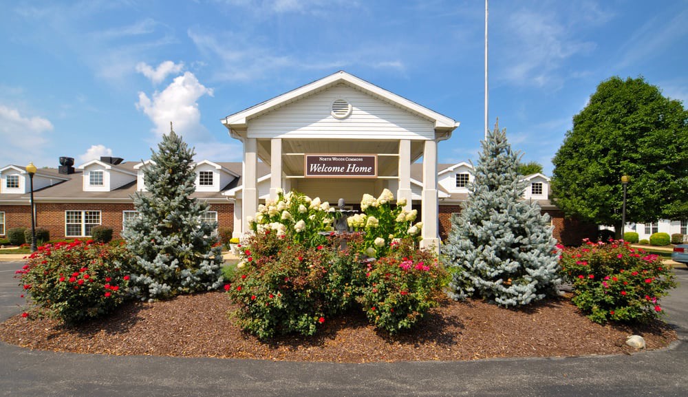 A well-maintained building entrance with lush landscaping and clear blue sky.