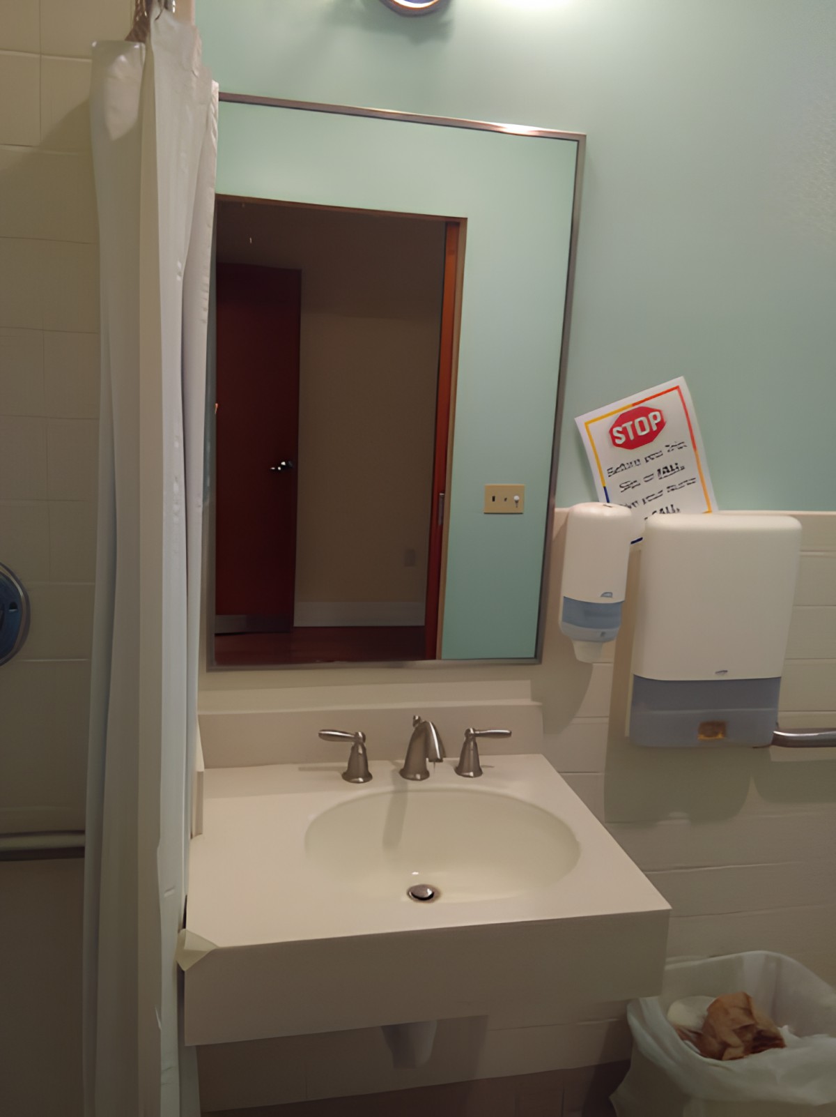 A public restroom featuring a sink with a mirror and paper towel dispensers.