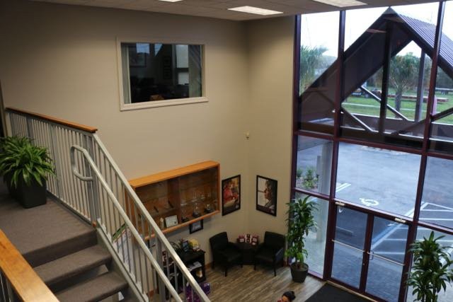 A modern office lobby featuring a staircase, seating area, and large windows.