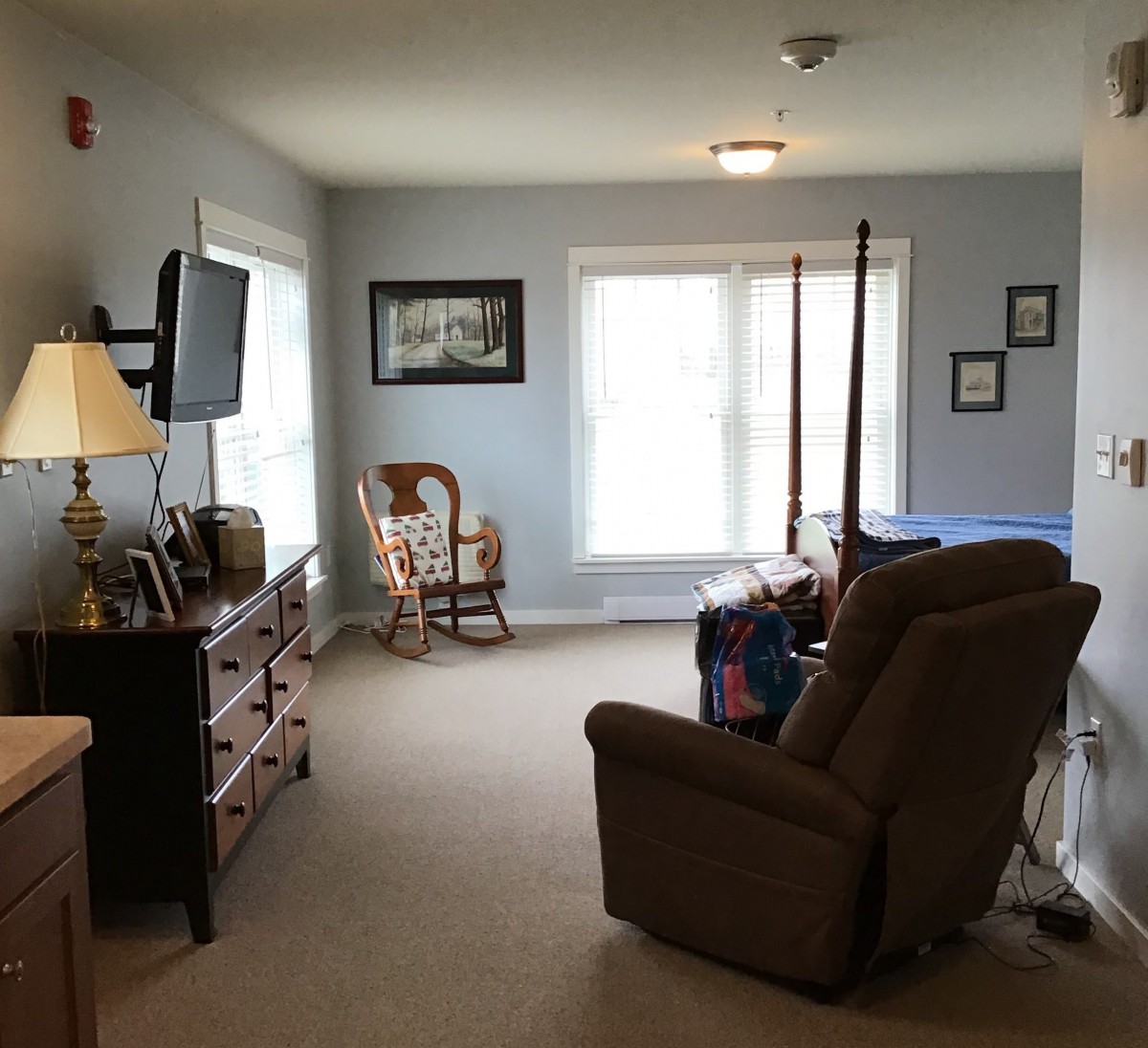 A cozy living room with a recliner, television, and rocking chair by the window.