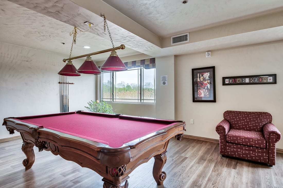 A stylish billiards room featuring a red felt pool table and cozy seating.