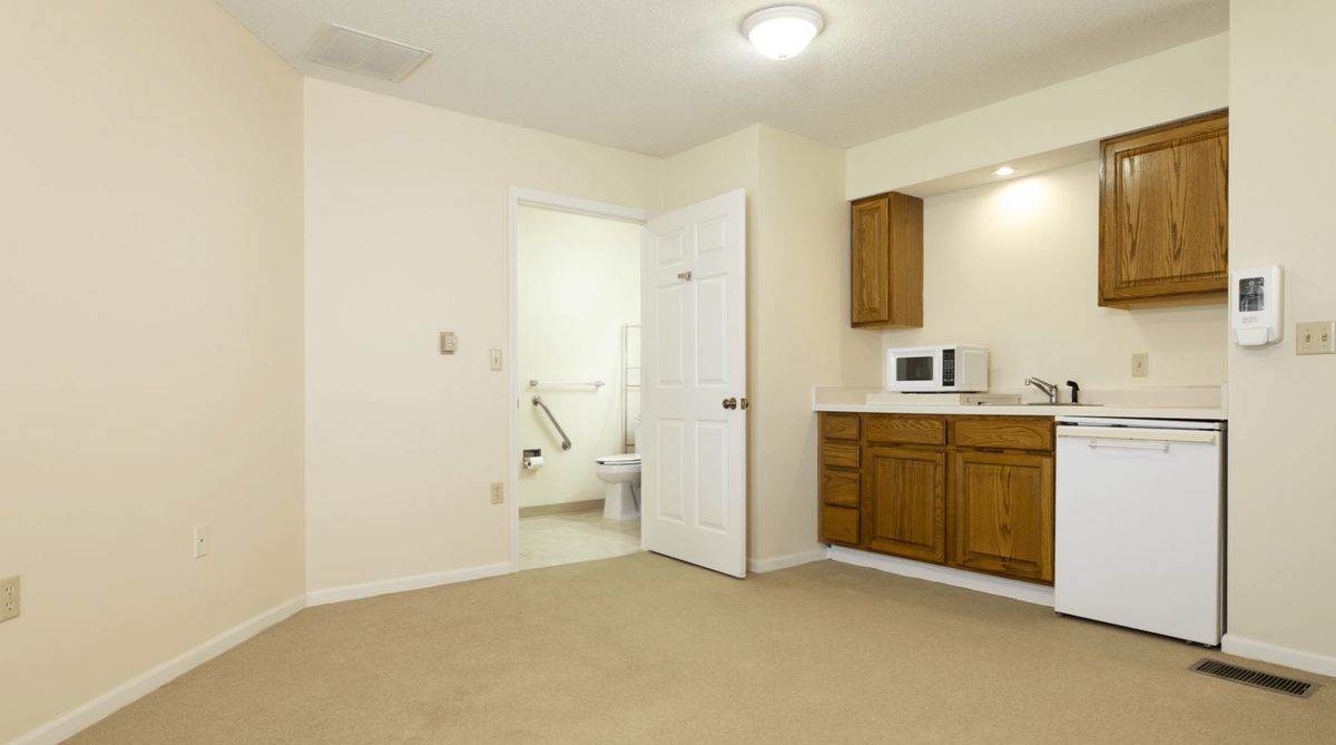 Minimalist apartment interior with a connected bathroom and kitchenette.
