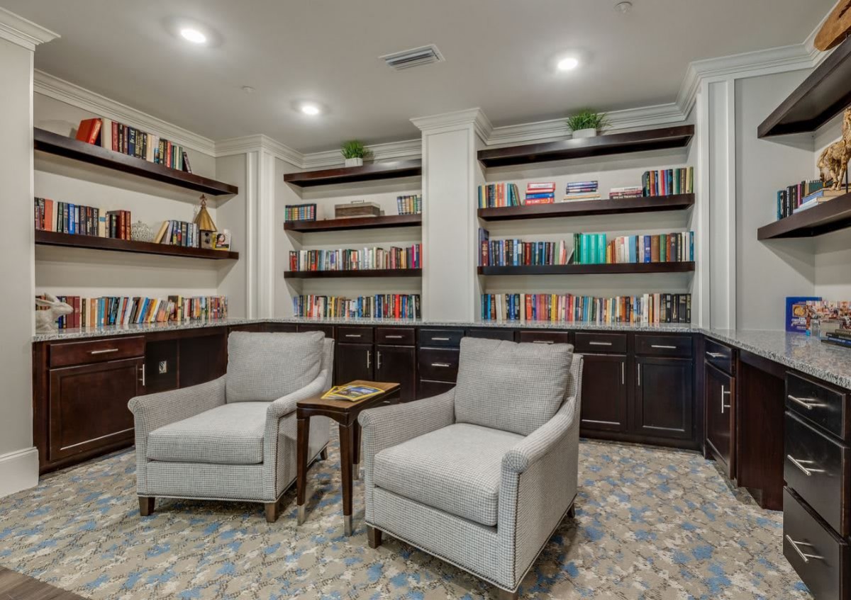 A cozy library with armchairs and bookshelves lined with books.